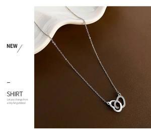 Detail of silver titanium steel interlocking heart pendant necklace on brown matte surface