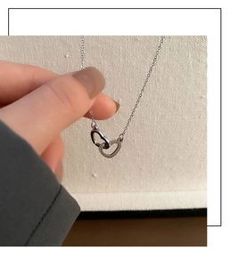 Detailed view of silver interlocking double heart pendant on a delicate chain
