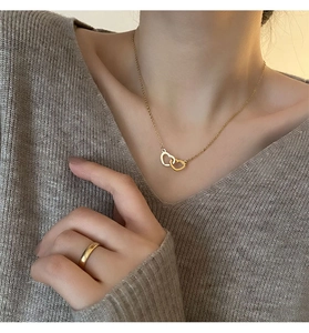 Detail of elegant gold double-heart necklace and matching ring on female model