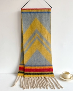 Detailed close-up of thick knit scarf with blue and yellow geometric patterns and tassels