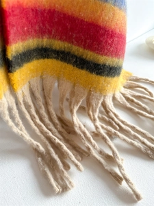 Detail of soft rainbow stripe knit scarf featuring colorful texture and beige tassels
