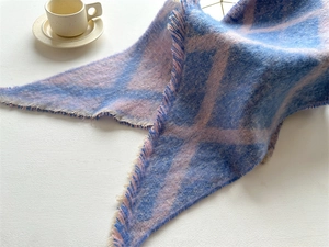 Détail d'une écharpe à carreaux bleus et roses avec des bords à franges et pompons
