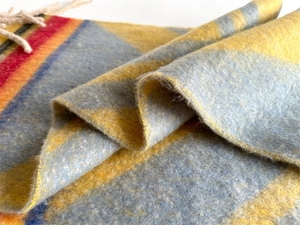 Macro shot of thick plaid scarf featuring soft fleece texture and cream fringed edges