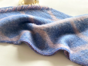 Détail d'une écharpe en maille à carreaux bleu et rose avec des franges délicates