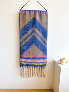 Detail of thick knit scarf with herringbone pattern and colorful tassel fringes