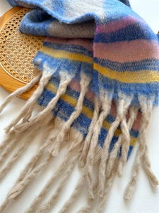 Close-up of thick colorful striped scarf with long tassels and soft fluffy texture