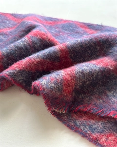 Gros plan d'une écharpe épaisse à carreaux rouge et bleu avec texture peluche et franges
