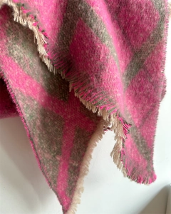 Détail d'une écharpe à carreaux rose et gris avec texture douce et bords à franges
