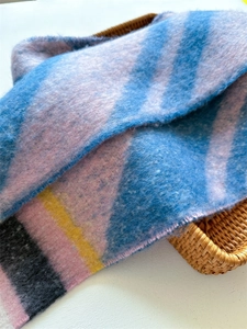 Detailed macro view of colorful striped mohair scarf texture in a woven basket