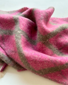 Gros plan d'une écharpe à carreaux rose et gris avec texture douce et détails de franges