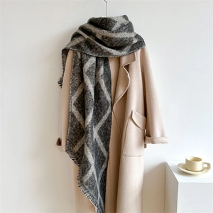 Détail d'une écharpe à carreaux gris et blanc avec franges sur un manteau en laine