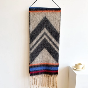 Detail of bohemian knit scarf featuring geometric patterns, vibrant stripes and long tassels