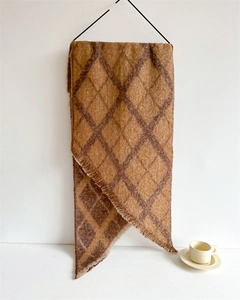 Détail d'une écharpe vintage à carreaux géométriques marron caramel avec des franges
