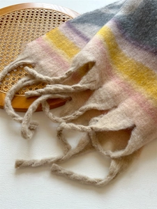 Detail of colorful striped scarf with thick fringe on a rustic woven basket