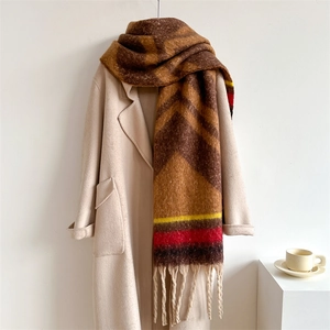 Thick knit color-block scarf with fringes styled on a trench coat in a cozy winter setting