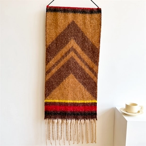 Detail view of a woven boho tapestry with geometric V-patterns and colorful tassels
