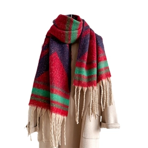 Thick oversized tassel scarf in red green plaid worn on a beige wool coat