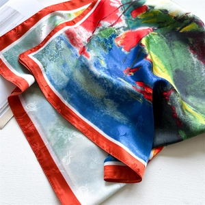 Detail of artistic oil painting silk scarf featuring vibrant lotus patterns and red borders