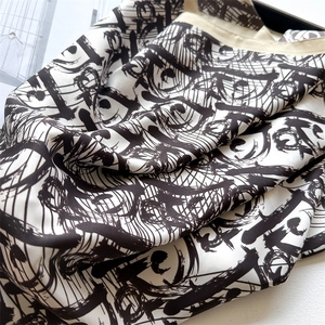 Detail of luxury silk scarf with black ink abstract print and high-end rolled edges