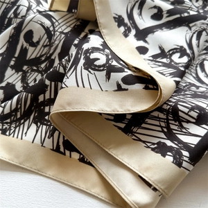 Detail of satin scarf showing abstract ink patterns and precise edge stitching