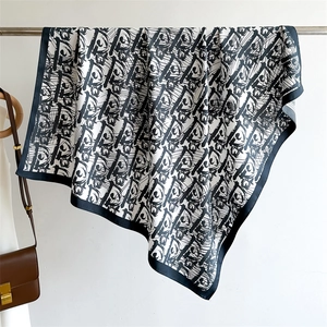 Detail of luxury silk scarf with black and white monogram pattern and natural sheen finish