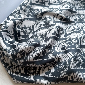 Close-up of luxury silk scarf showing intricate twill weave and black graffiti print details