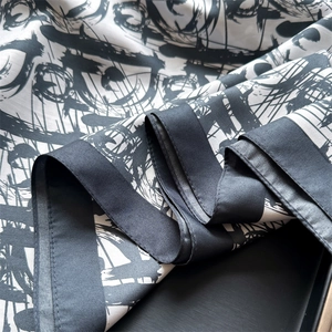 Detail of silk scarf with black and white abstract ink print and smooth satin texture