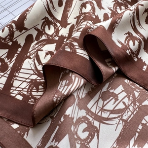 Detailed view of luxury silk scarf showing twill texture and abstract brown patterns