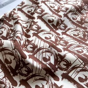 Close-up of silk twill scarf fabric featuring elegant letter print and satin texture