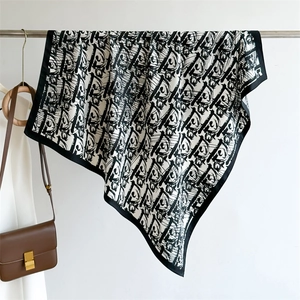 Detail of silk-satin scarf with black and white letter patterns draped on a bag