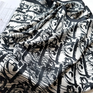 Detailed close-up of premium black and white silk scarf with abstract letter prints