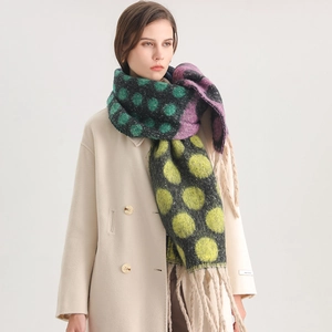 Detail of soft winter shawl featuring colorful dots and thick tassels on wool-like fabric