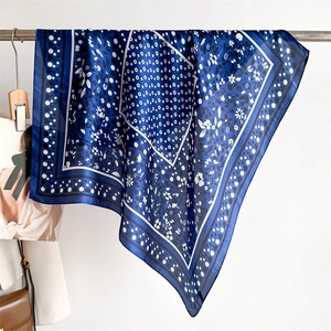 Detail of navy blue silk scarf featuring elegant white floral patterns and soft drape folds