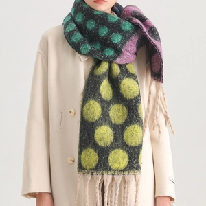 Detail of soft thick wool scarf featuring colorful oversized polka dots and long tassels