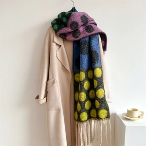 Detail of colorful polka dot scarf with tassels on a beige coat in home setting