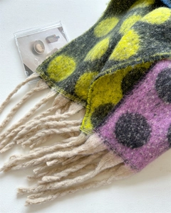 Detail of thick wool-like scarf featuring large contrast polka dots and long chunky tassels