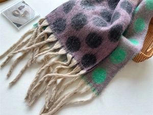 Detailed view of thick knit scarf with purple and black polka dots and fringe