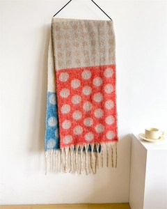 Close-up of a warm polka dot scarf with red and blue color blocks and tassel details