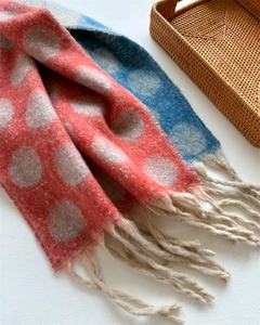 Detailed texture of thick knitted scarf with colorful polka dots and fringe tassels