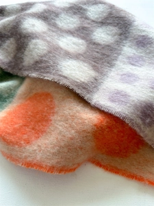 Close-up of thick faux wool scarf showing soft fuzzy texture and vibrant polka dot patterns