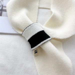 Detail shot of soft white knitted scarf featuring contrast loop buckle and fluffy texture