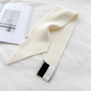 Detail of cream knitted scarf featuring black and white striped end and soft texture
