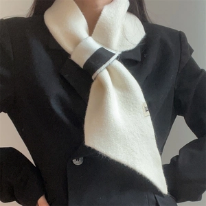 Detail of a black and white knitted scarf featuring a cross-through loop and branded label
