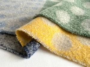 Detailed view of soft wool-like scarf featuring colorful polka dots and fringe edges