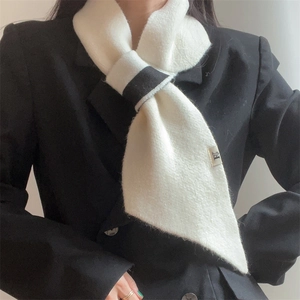 Close-up of black and white knitted scarf with crossover design and brand tag