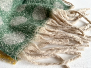 Detailed close-up of green polka dot scarf showing soft knit texture and long beige tassels