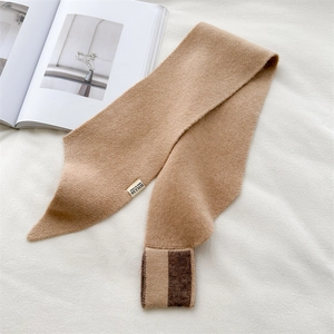Detail of camel knitted cross scarf with logo label on minimalist white background