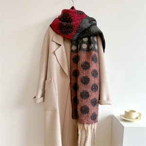 Detailed close-up of thick polka dot scarf with fringes on beige wool coat
