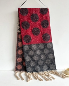 Detail of color-block knit scarf with contrast polka dots and thick cream fringe tassels