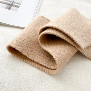 Detailed close-up of beige knitted scarf texture next to a magazine for winter fashion